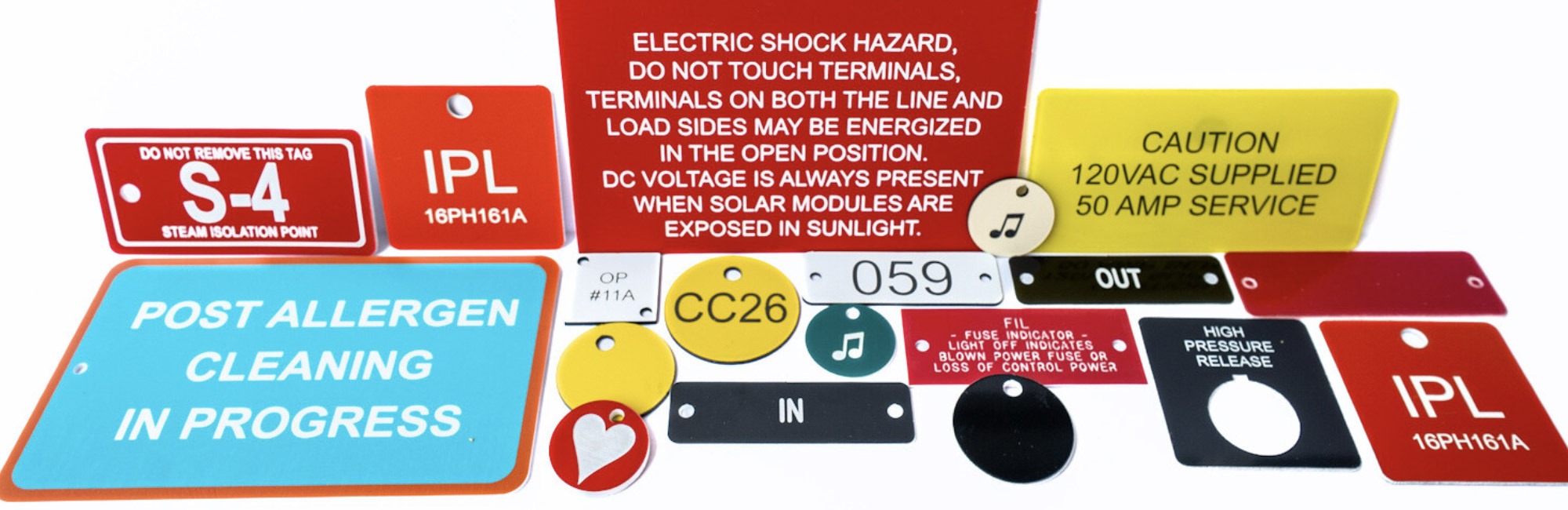 Engraved and printed plastic industrial tags in various colors and shapes, used for labeling equipment and machinery